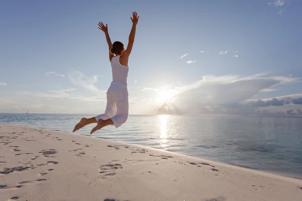 Glad ung kvinna hoppar på stranden — Stockfoto
