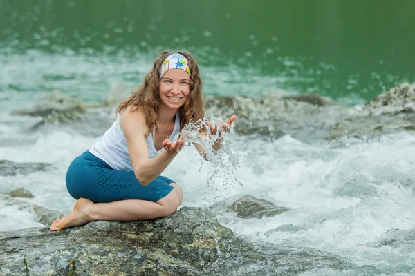 Girl drinks clear water from mountain river Stock Picture