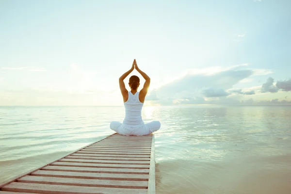 Mujer caucásica practicando yoga en la orilla del mar Imagen de stock