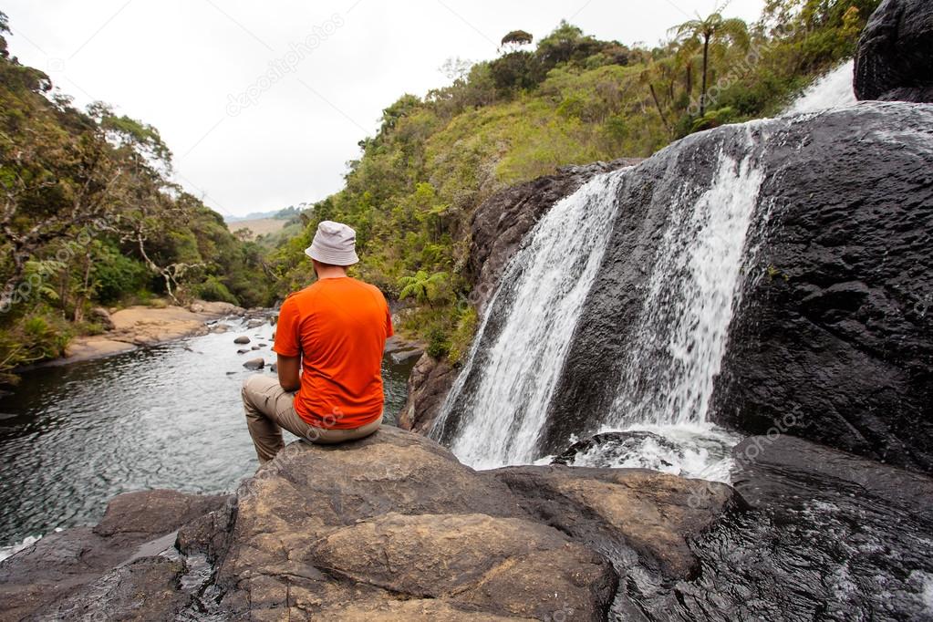 Trekker looks at wild waterfall in Horton Plains National Park,