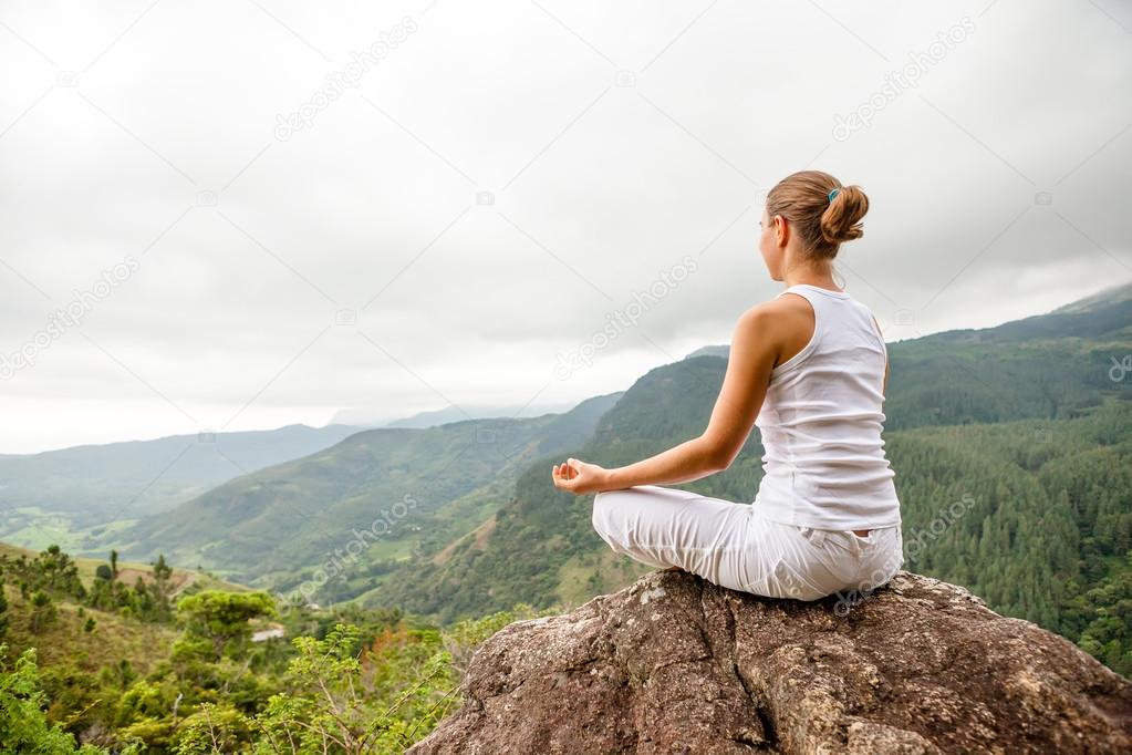 Woman is doing yoga exercises in mountains