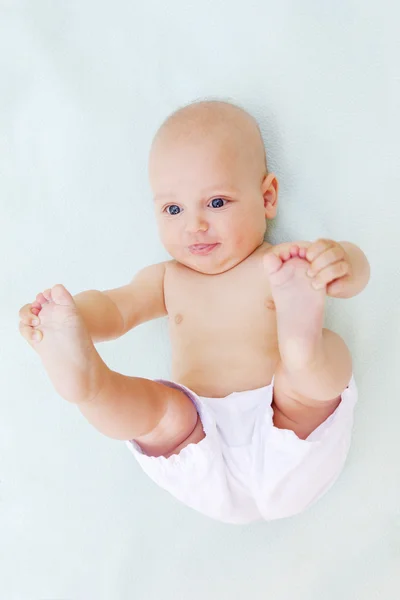 Baby boy plays alone on white towel — Stock Photo, Image