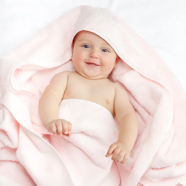 Caucasian baby boy covered with pink towel joyfully smiles at ca — Stock Photo, Image