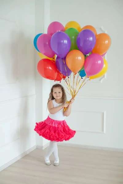 Kleines Mädchen spielt im Studio mit bunten Luftballons — Stockfoto