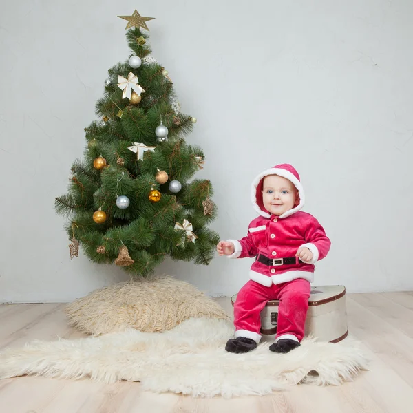 Small boy in Santa suit plays in white studio — Stock Photo, Image