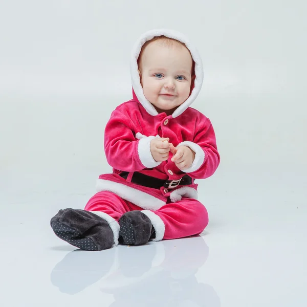 Menino pequeno no terno de Santa joga perto da árvore de ano novo no estúdio branco — Fotografia de Stock