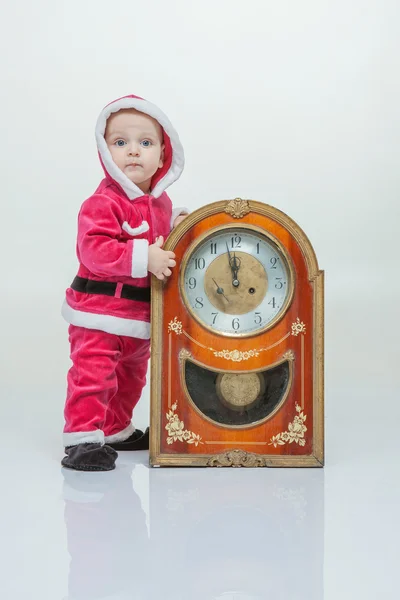 Malý chlapec v obleku Santa hraje s vintage hodiny v bílém studio — Stock fotografie
