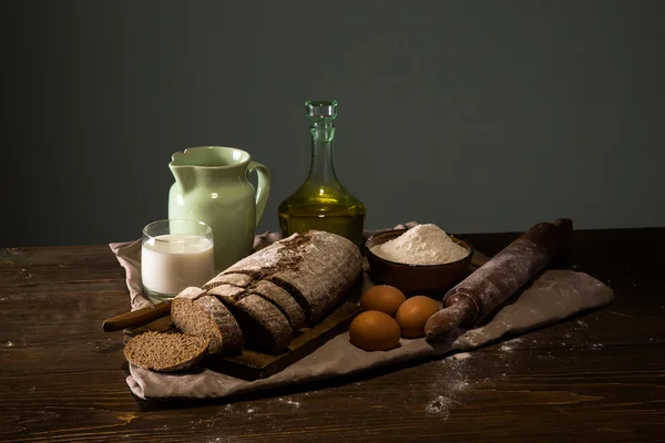 Still life photo of bread and flour with milk and eggs at the wo — Stock Photo, Image