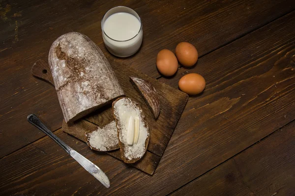 Kenyér, vaj és a tojás, a woodent asztal-ban alacsony-könnyű sty — Stock Fotó