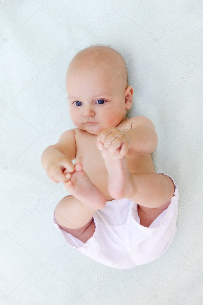 Baby boy plays alone on white towel