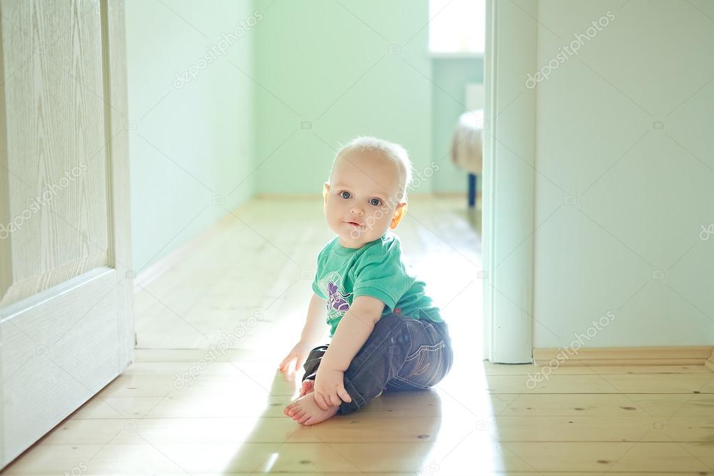 Chubby baby boy sitting on wooden floor at home