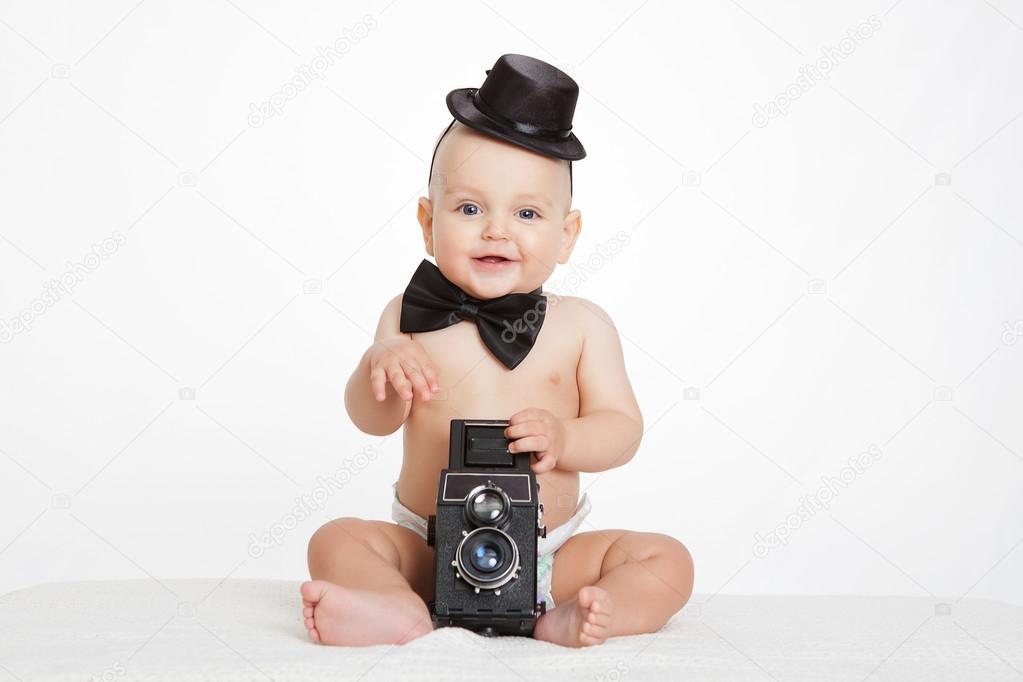 Caucasian baby boy plays with vintage camera an smiles joyfully