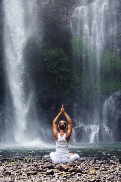 Woman meditating doing yoga between waterfalls — Stock Photo, Image