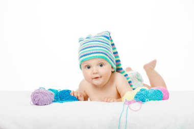 İplik topları arasında komik renkli şapkalı beyaz şirin çocuk