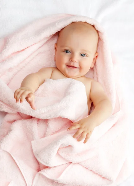Caucasian baby boy covered with pink towel joyfully smiles at ca — Stock Photo, Image