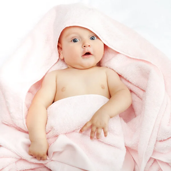 Caucasian baby boy covered with pink towel joyfully smiles at ca — Stock Photo, Image