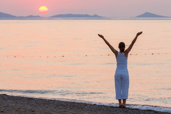 Kvinnan gör morgonen övningar på havet under sunrise — Stockfoto