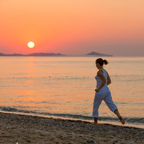 Kvinnan gör morgonen övningar på havet under sunrise — Stockfoto