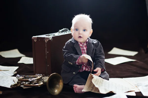 Caucásico bebé niño juega con trompeta entre sábanas con música —  Fotos de Stock