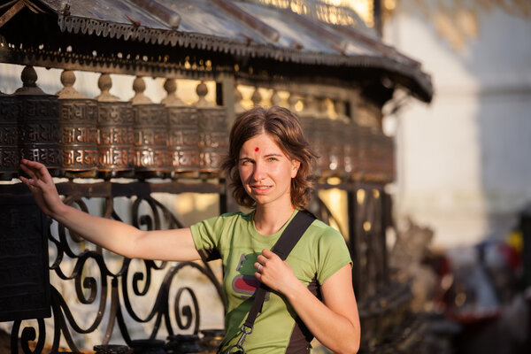 Женщина касается молитвенного колеса в непальском храме swayambhunath
