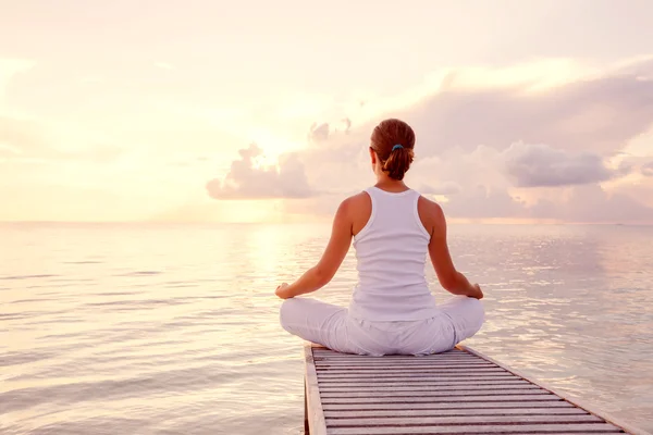 Kaukasisk kvinna utövar yoga på stranden — Stockfoto