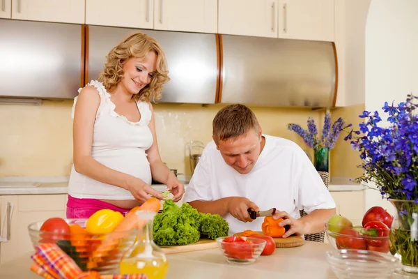 Mulher grávida e seu marido preparam salada de legumes em casa — Fotografia de Stock