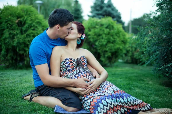 Беременная пара позирует в парке — стоковое фото