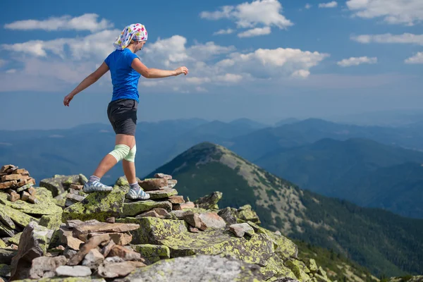 Mujer atleta está saltando sobre piedras en las montañas — Foto de Stock