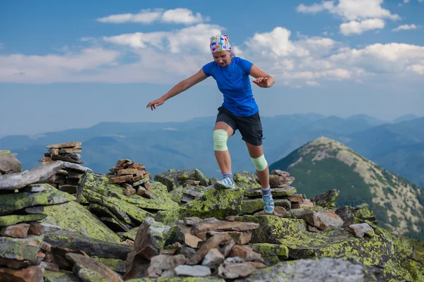 Kvinnan idrottsman är att hoppa över stenar i bergen — Stockfoto
