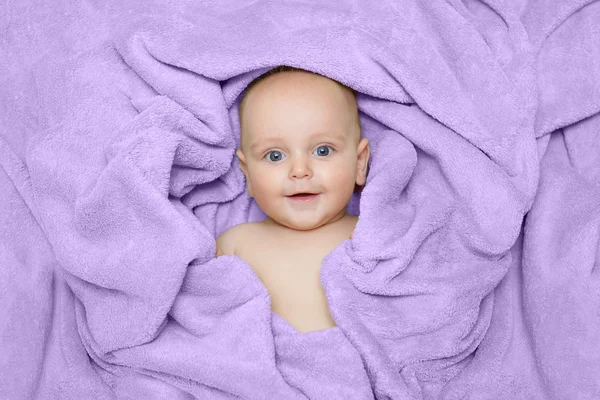 Caucasian baby boy covered with green towel joyfully smiles at c — Stock Photo, Image