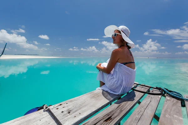 Kaukasische vrouw vindt rest op houten pier tot Indische Oceaan — Stockfoto