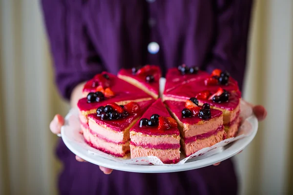 Sweet sliced cake at white plate in woman's hands