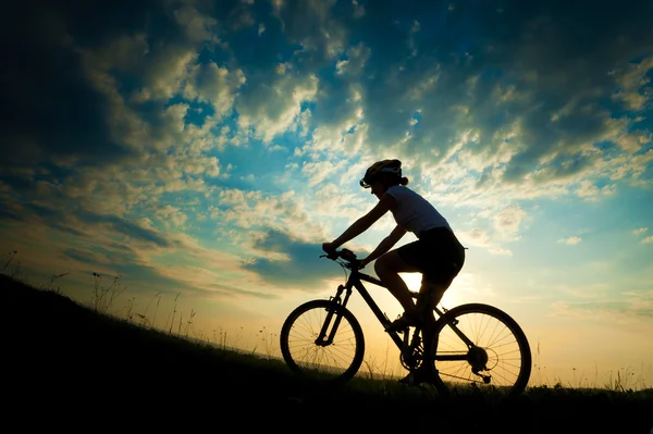 Biker-girl at the sunset on the meadow