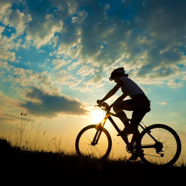 Biker-Mädchen bei Sonnenuntergang auf der Wiese — Stockfoto