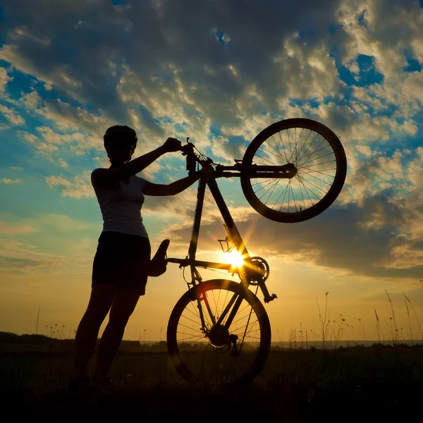 Biker-Mädchen bei Sonnenuntergang auf der Wiese — Stockfoto