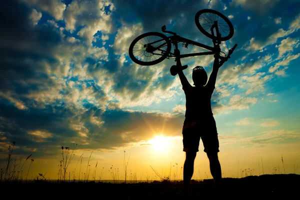 Biker hält Fahrrad hoch in den Himmel — Stockfoto