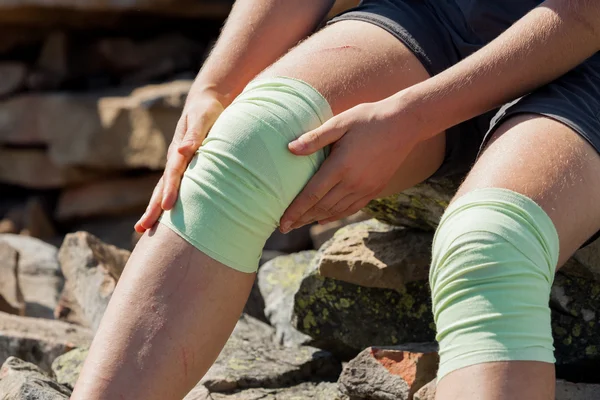 Dziewczyna szuka Athlet rozwiązuje bandaż na zewnątrz kolana — Zdjęcie stockowe