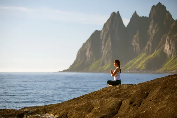 Genç kadın arasında Norveç dağlarında yoga uygulamak