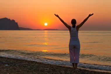 Kadın sabah excercises denizde gündoğumu sırasında yapıyor