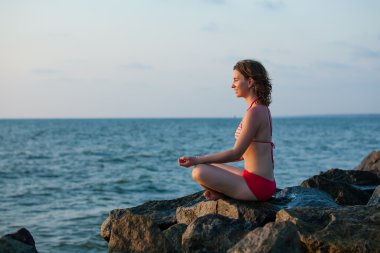 Denizde günbatımı sırasında meditasyon kadın