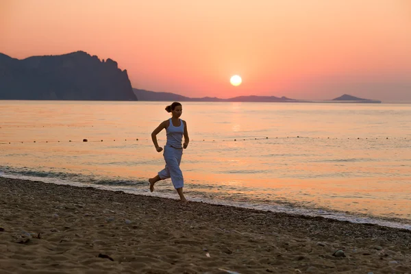 Kvinnan gör morgonen övningar på havet under sunrise — Stockfoto