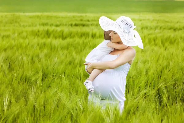 Беременная мать и ее дочь веселятся на открытом воздухе — стоковое фото