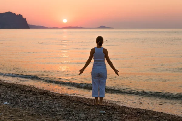 Donna sta facendo esercizi mattutini al mare durante l'alba — Foto Stock