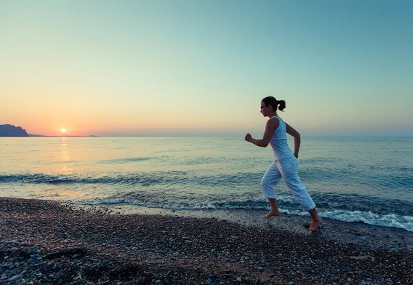 Kvinnan gör morgonen övningar på havet under sunrise — Stockfoto