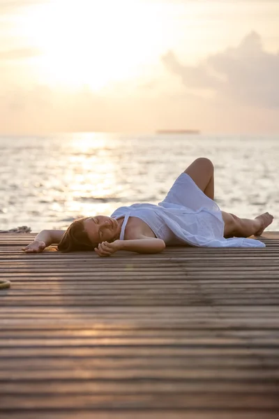 Kaukasische vrouw vindt rest op houten pier tot Indische Oceaan — Stockfoto