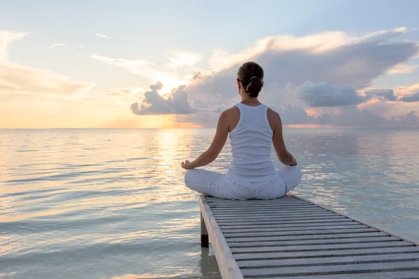 Kaukasisk kvinna utövar yoga på stranden — Stockfoto