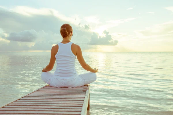 Kaukasisk kvinna utövar yoga på stranden — Stockfoto