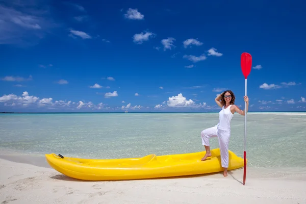 Mulher caucasiana jovem mantém remo na praia perto de k amarelo — Fotografia de Stock
