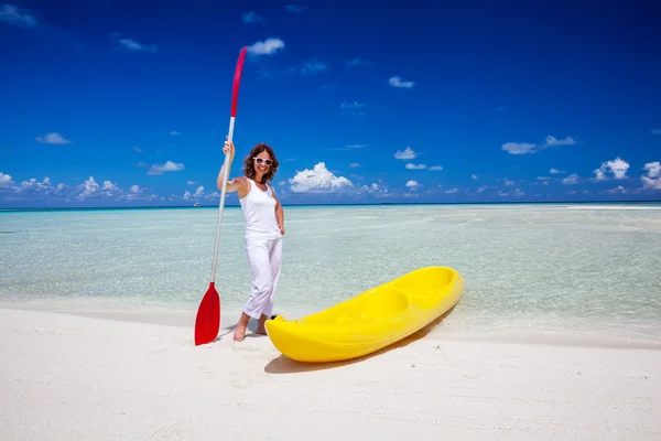 Young caucasian woman keeps paddle at the seashore near yellow k