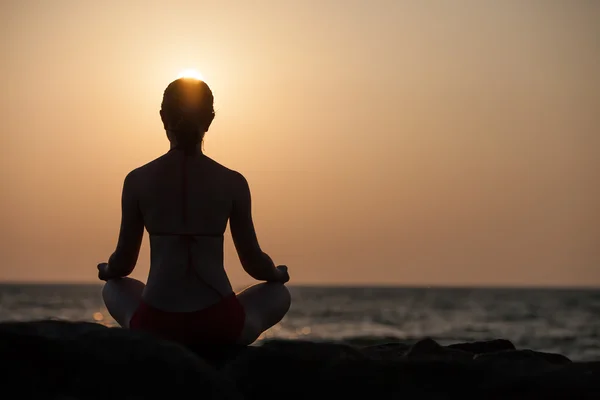 Silueta de mujer que medita en el mar al atardecer — Foto de Stock